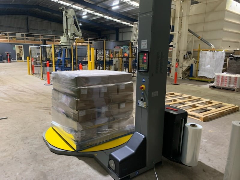 Autaomatic pallet wrapping machine with goods on it in a warehouse